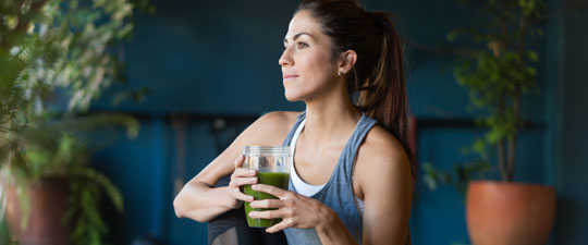 young woman drinking a smoothie after exercising