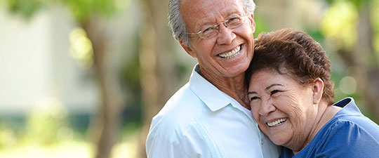 Senior couple smiling and hugging outside