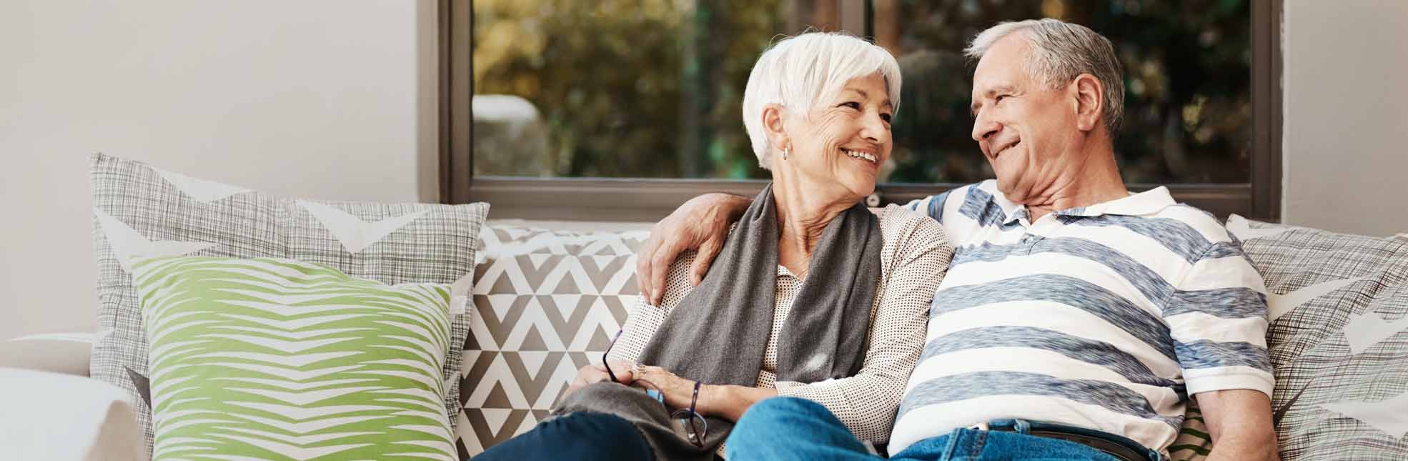 senior couple sitting on couch and smiling