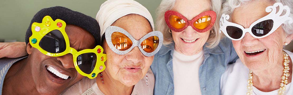 Four senior ladies wearing crazy sunglasses and smiling